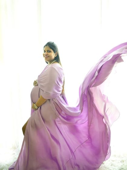 The high-key lighting and flowing lavender fabric create an angelic and ethereal feel in this beautiful solo maternity portrait.