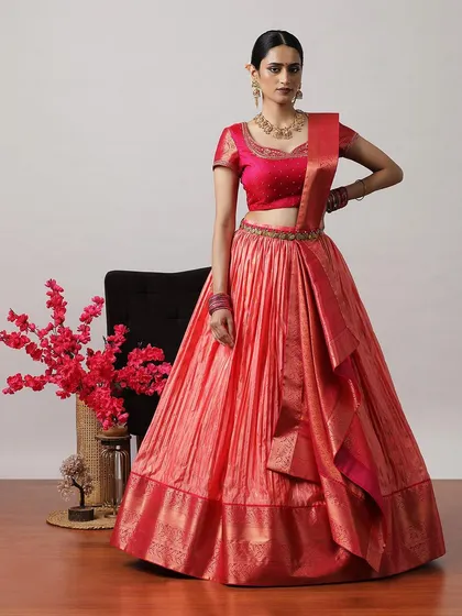 A vibrant coral-pink lehenga with a matching embroidered blouse and a rich Banarasi border. A bright and cheerful choice for daytime celebrations.
