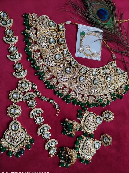 A full bridal set in green Kundan, featuring a heavy necklace, mathapatti, and other matching accessories.