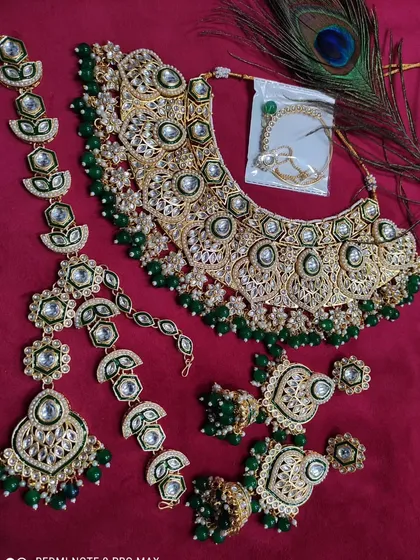 A full bridal set in green Kundan, featuring a heavy necklace, mathapatti, and other matching accessories.