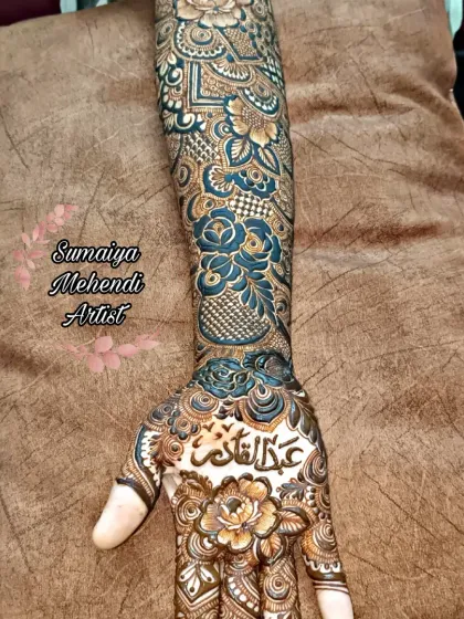 A full arm floral henna design with a name written in Arabic calligraphy on the palm. The use of shading gives the flowers a beautiful, almost three dimensional look.