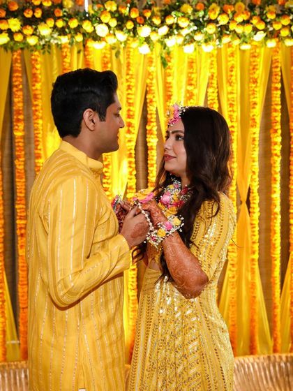 A lovely couple moment during their Haldi. The background of yellow drapes and floral strings creates a warm and intimate setting for their celebration.