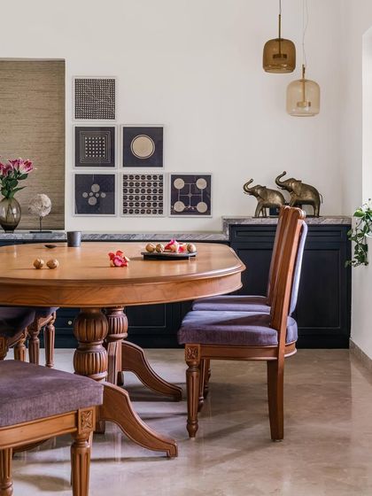 The dining area in Relic House exudes vintage charm with its intricately carved wooden table and chairs upholstered in a deep purple fabric. We curated a gallery wall of block-print art and added brass elephant figurines to complete this elegant, culturally rich space.