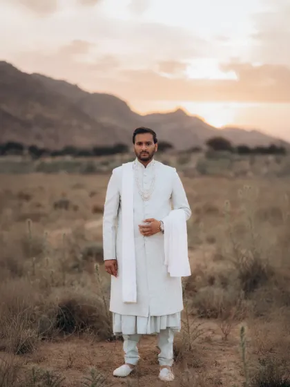 A solo portrait of Malay looking out at the horizon during his destination pre-wedding shoot. The soft, warm light of the setting sun creates a calm and majestic mood.