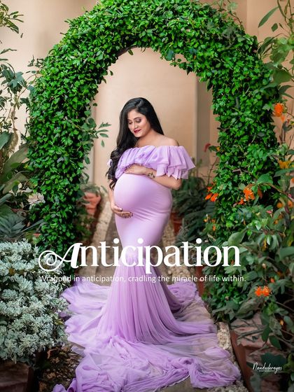 Framed by a living arch of green leaves, the mother-to-be cradles her bump in a moment of pure anticipation. A beautiful example of a garden maternity portrait.