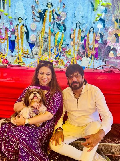 A perfect family portrait at our pet-friendly pandal. A couple sits with their beautifully dressed Shih Tzu in front of the Maa Durga idol, capturing a priceless festive memory.