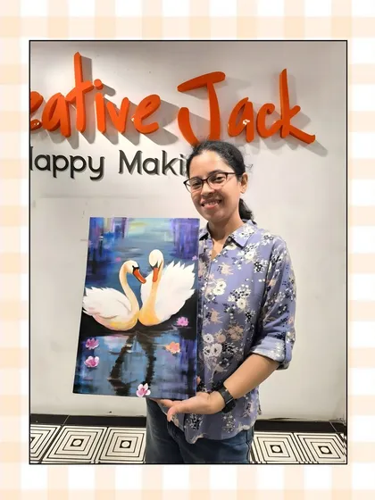 A participant holds her serene painting of two swans on the water, a testament to the skills she learned in my beginner-friendly acrylic painting class.