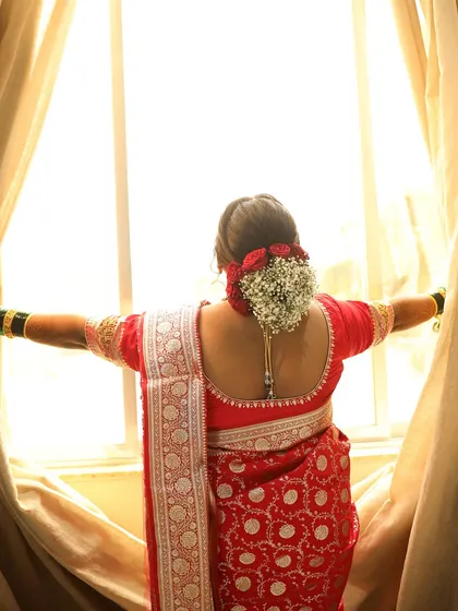 A beautiful shot capturing the back of the bride's look, highlighting the floral bun and the elegant saree.
