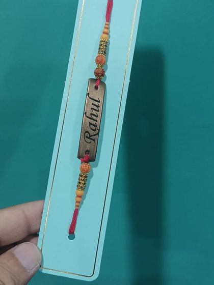 Another look at the personalized name Rakhi, showing the beautiful threadwork and the engraved nameplate.