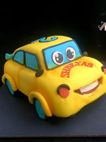A 3D sculpted cake of a cute, smiling yellow car character.