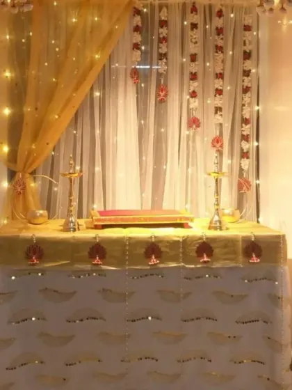 This is a simple yet beautiful Ganpati decoration for a small space at home. The setup uses elegant drapes, warm fairy lights, and traditional brass diyas to create a sacred and peaceful corner for the festival.