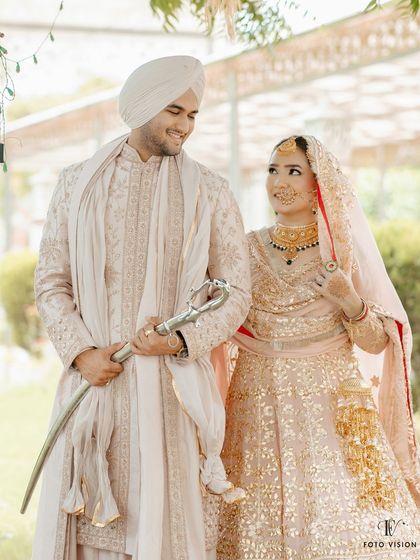 A candid, happy moment between the bride and groom, showcasing the groom's traditional kirpan and the couple's joyful interaction after their Anand Karaj.