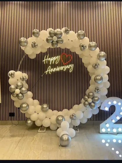 Celebrating a big milestone? I design elegant anniversary decorations like this one for a 25th wedding anniversary. A custom "Happy Anniversary" neon sign inside a chic white and silver balloon ring, paired with large light-up numbers, makes for a classy celebration.