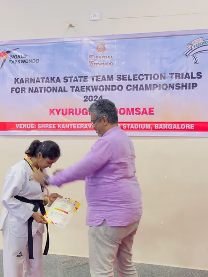 A moment of pride as one of our female black belt students receives her medal and certificate at the state championship.