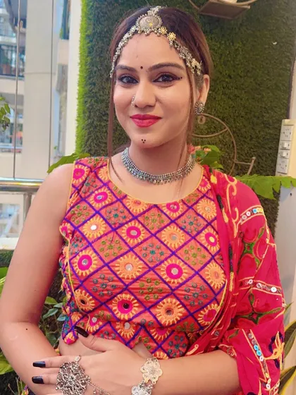 A model showcasing a vibrant pink and orange mirror work blouse, paired with oxidized silver jewellery for a complete Navratri look.