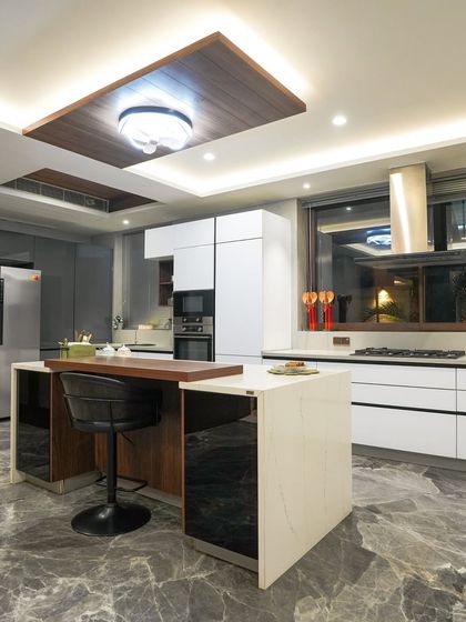 This angle shows the two-tiered island design, which includes a raised wooden bar for seating. This feature cleverly separates the cooking zone from the dining area.