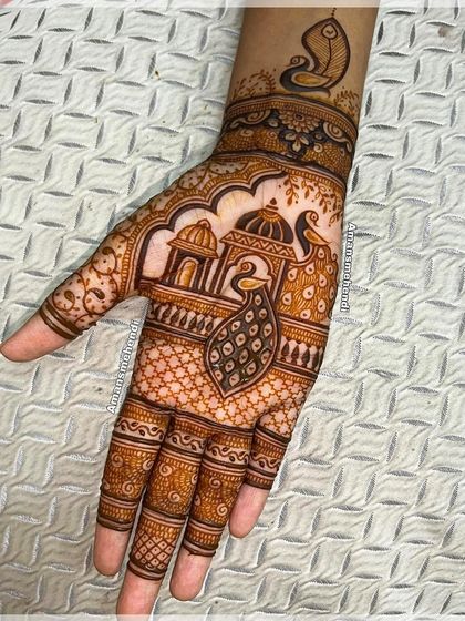 A beautiful design with a peacock in front of a palace on the palm. The wrist features a conch shell (shankh), an auspicious Hindu symbol.