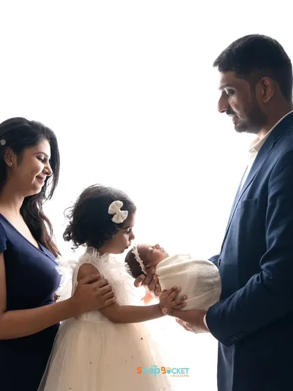 A full family portrait with the newborn baby as the star. The high-key lighting creates a bright, airy, and timeless feel, perfect for newborn photography.