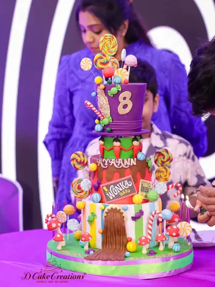 The moment before the candles are blown out on the Willy Wonka cake, showing all the colorful and fun candy decorations.