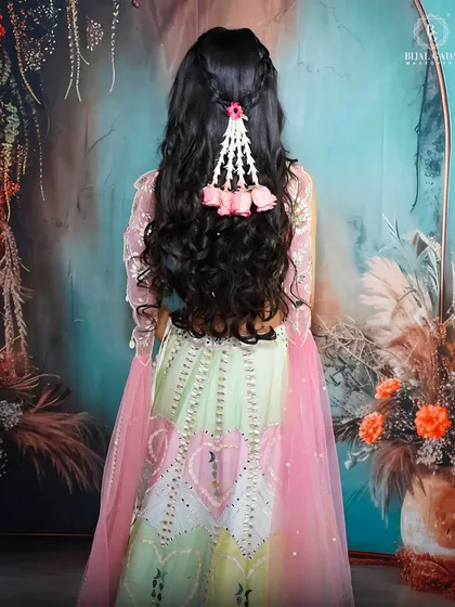 The back view of this hairstyle shows a simple braid adorned with delicate floral accessories. It’s a sweet and charming detail that completes the fairytale look.