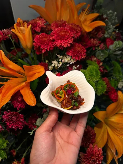 A small portion of a flavourful Asian dish, served in a leaf-shaped bowl, demonstrating our attention to detail in plating.