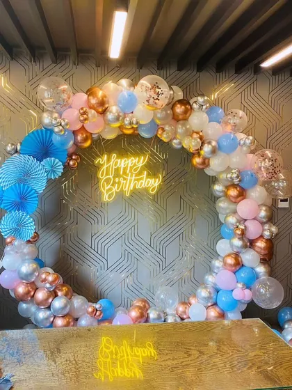 A beautiful ring backdrop with a mix of pastel blue, pink, white, and rose gold balloons, accented with blue paper fans.