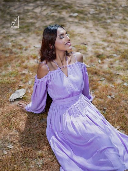 A serene moment captured as the model sits on the grass, basking in the sunlight. This shot highlights the soft, flowing fabric of the dress.