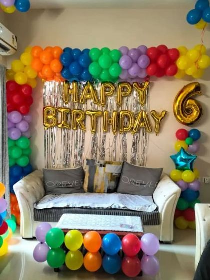 A rainbow-themed 6th birthday party at home with a colorful balloon arch.
