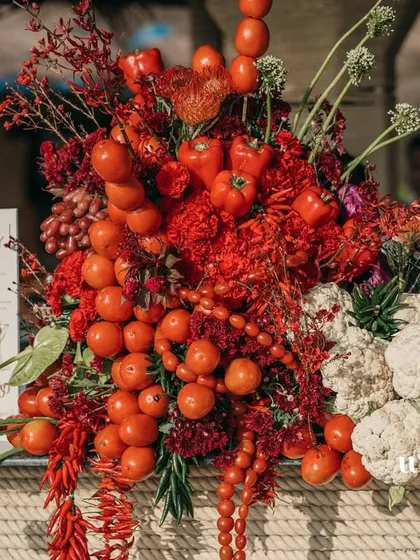 A vibrant arrangement of red fruits and vegetables, including tomatoes and cauliflower, used as decor for the bar.