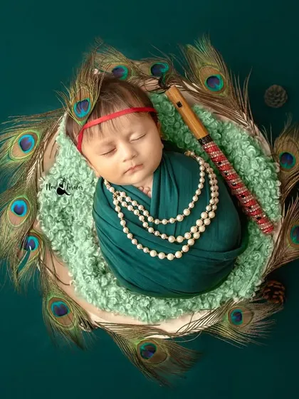 This serene portrait captures a sleeping newborn as Kanha, holding his flute. The composition is balanced and artistically styled.