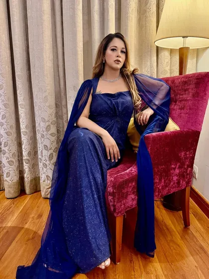 A quiet moment of glamour in a sparkling blue gown before the show begins.
