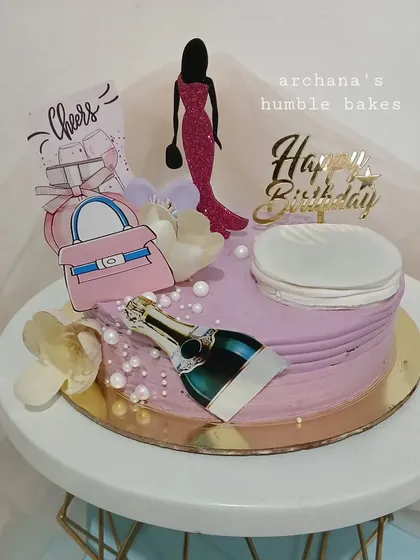A chic cake for an 18th birthday, decorated with champagne, a handbag, and other fun toppers.