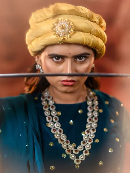 It's more than a costume; it's about embodying a character. Here, we capture the fierce intensity of Rani Lakshmibai, with a focus on the determined expression, period-accurate pagri, and the powerful presence of the warrior queen.