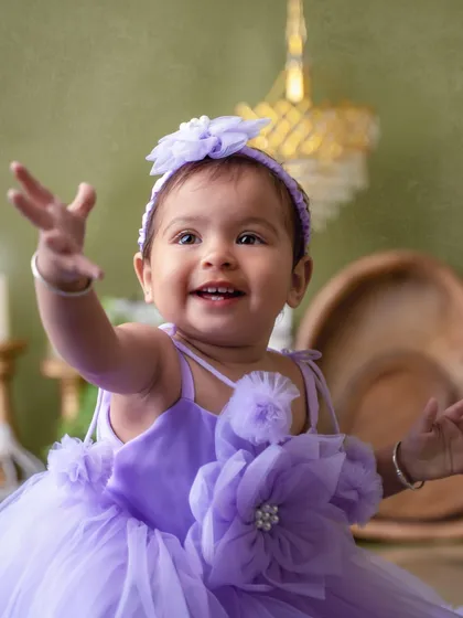 Reaching out with a happy smile. This pre-birthday shoot in a lovely lavender dress is a perfect way to celebrate turning one.
