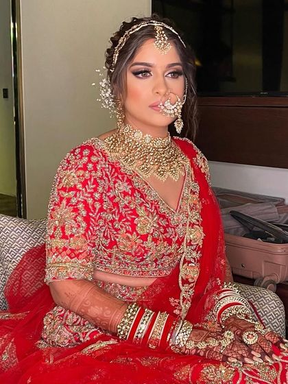 A messy, textured look for a modern bride. The hairstyle adds a touch of softness to the traditional red lehenga.