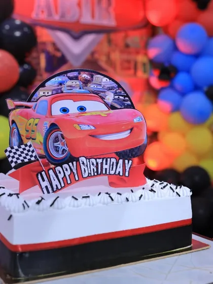 A close-up of the Lightning McQueen topper on one of the flat cakes, showing the fun and detailed design.