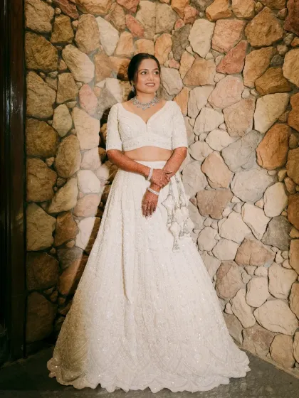 A full-length shot of the bride against a stone wall, looking absolutely stunning.