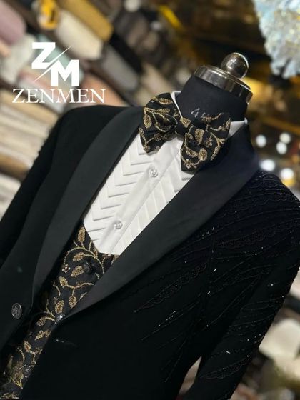 A close-up of the black and gold tuxedo, focusing on the contrast between the patterned waistcoat and the sleek black jacket.