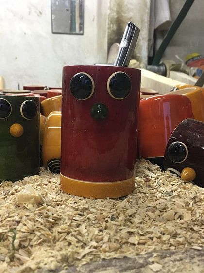 A closer look at our owl pen holders, nestled in a pile of wood shavings. This view highlights the glossy lacquer finish, which is achieved using a unique friction polishing method with pandanus leaves.