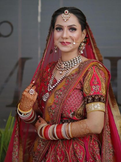A full portrait of a bride in a stunning red and yellow lehenga. Her makeup is classic and timeless, with a beautiful pearl and kundan jewelry set.