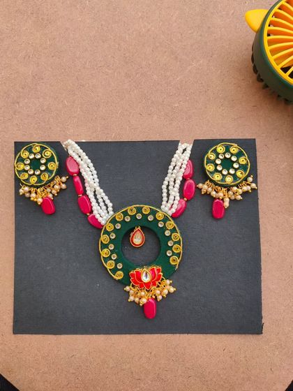A beautiful wedding collection piece featuring a dark green fabric base with intricate Kundan and zardozi work. The pop of red from the beads adds a classic bridal touch.