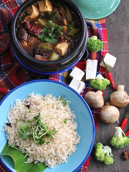 The Sichuan Claypot, presented with a side of fluffy brown rice. This dish is a perfect example of how we create bold, international flavors using only whole, plant-based ingredients.