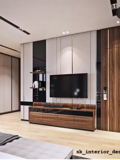 A master bedroom featuring a full wall dedicated to the TV unit and wardrobe. The combination of dark wood and glossy black panels creates a sleek, masculine aesthetic.