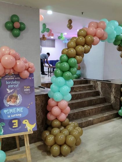 It's all in the details. A personalized welcome sign on an easel greets guests at the entrance, perfectly matching the dinosaur theme and color scheme of the main balloon arch decor.