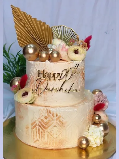 A classic two-tier cake in white and gold, elevated with intricate stenciling and modern gold toppers. This design is perfect for an elegant 20th birthday or an intimate engagement party.