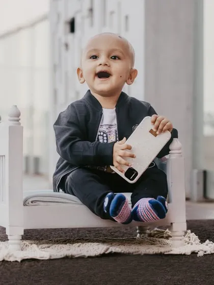 An expressive shot of a baby boy with a big, open-mouthed smile during his modern, urban-themed milestone session.