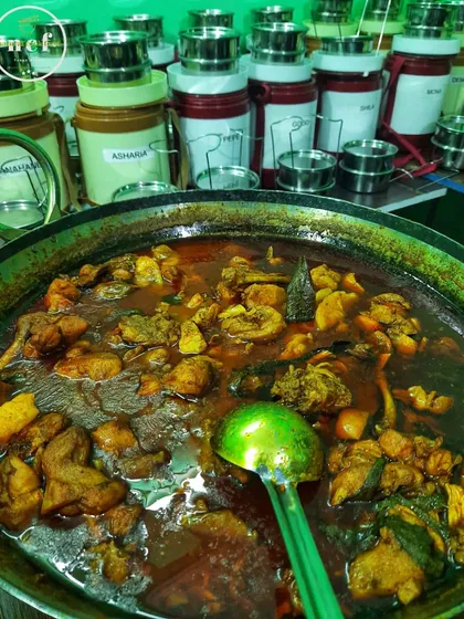 A huge pot of chicken curry being cooked for a large event, with my tiffin carriers in the background.