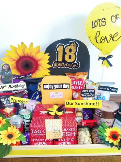 An 18th birthday is a huge milestone, and this 'sunshine' themed hamper is designed to be bright and cheerful. It's filled with snacks, a large sunflower, and personalized elements to celebrate the new adult.