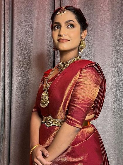 A full view of the elegant bridal look. The simple vaddanam and layered necklaces create a look that is both traditional and understated.