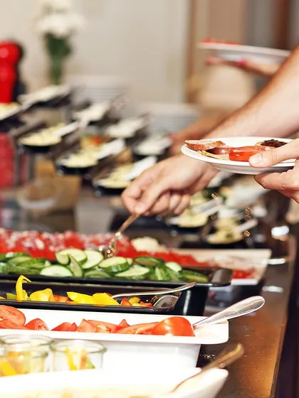 A guest helps themselves to a fresh and healthy salad bar at one of our catered events. We provide a wide array of options so everyone can build a plate that they love, ensuring a satisfying meal for all.